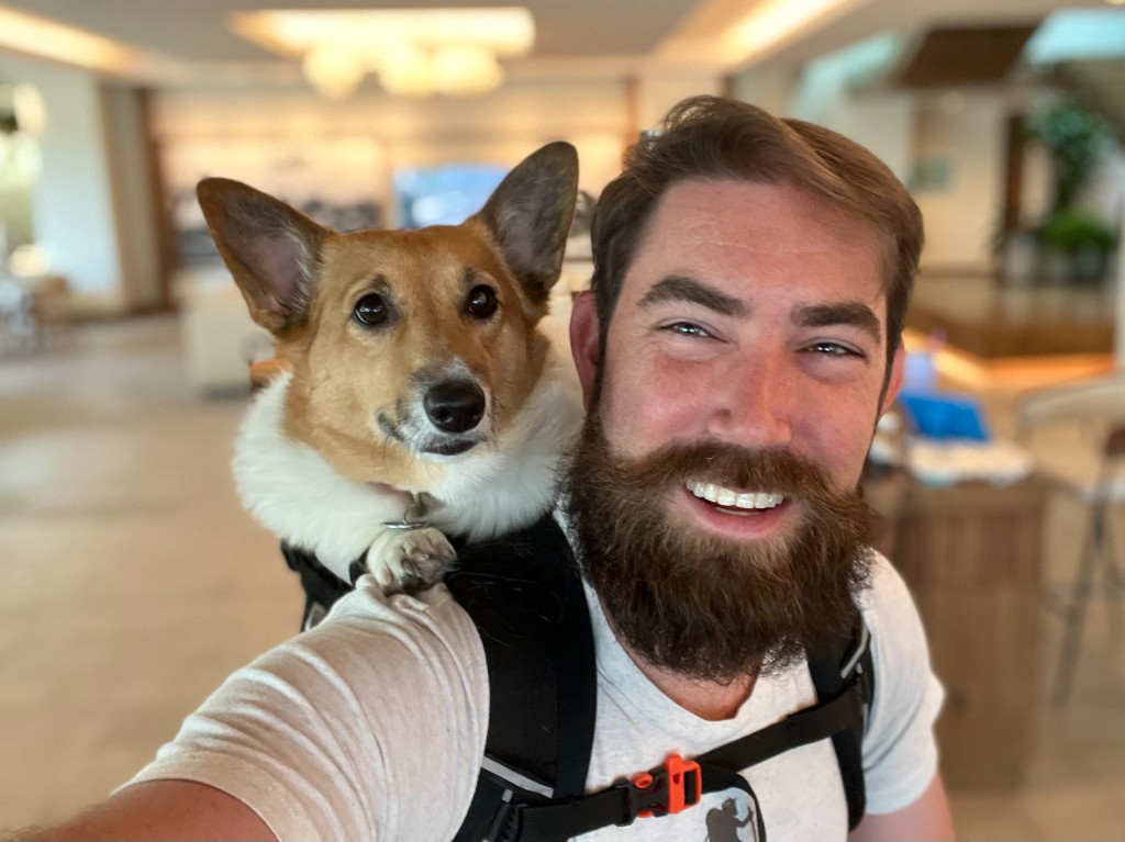 John Brandon Elam with a corgi in a backpack carrier
